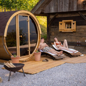 neptune-saunas-and-hot-tubs---customer-photo---Slovenia-2-person-barrel-suana-with-couple-enjoying-the-sun-loungers-next-to-it
