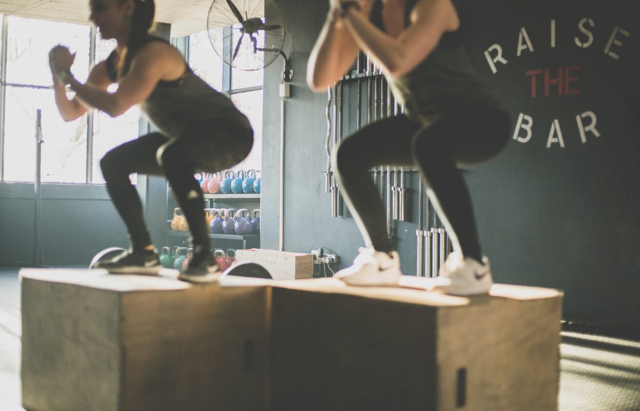 Neptune Saunas Blog - Benefits of taking a sauna after a workout - two women squatting during crossfit